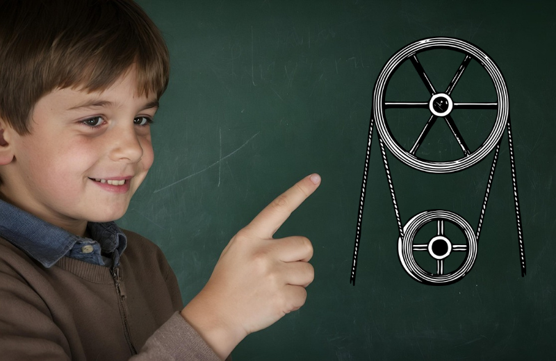 Uczeń klas 7–8 wskazuje na schemat kół pasowych na tablicy podczas zajęć z fizyki.