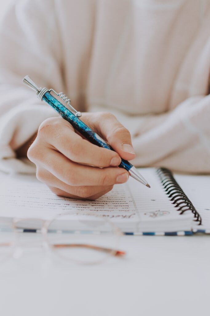 Kurs Roczny E8 1 Dłoń ucznia zapisująca rozwiązanie zadania z matematyki w zeszycie. Element mądrej pracy na rocznym kursie ósmoklasisty w Leonauce.